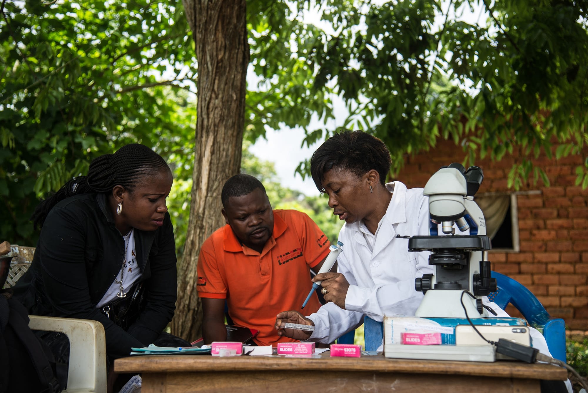 Researchers working in rural village with microscope