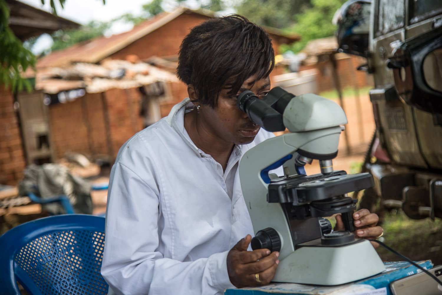 Health care worker examines sample under microscop in river blindness area