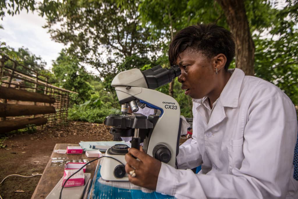 Healthworker looking in microscope in a village