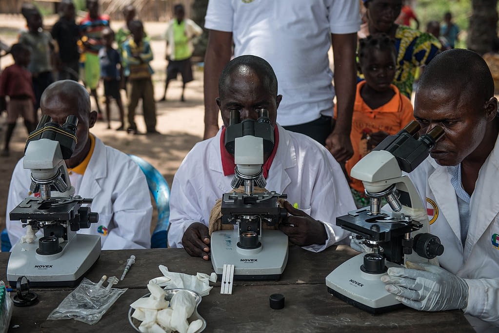 Healthworkers from mobile screening teams look through microscopes to check blood samples for sleeping sickness