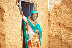 Woman standing in front of her door house in a rural village in Sudan
