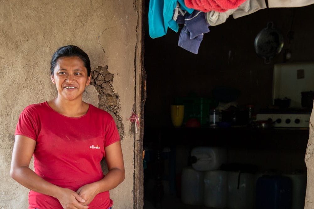 Woman in Guatemala stands in front of her house