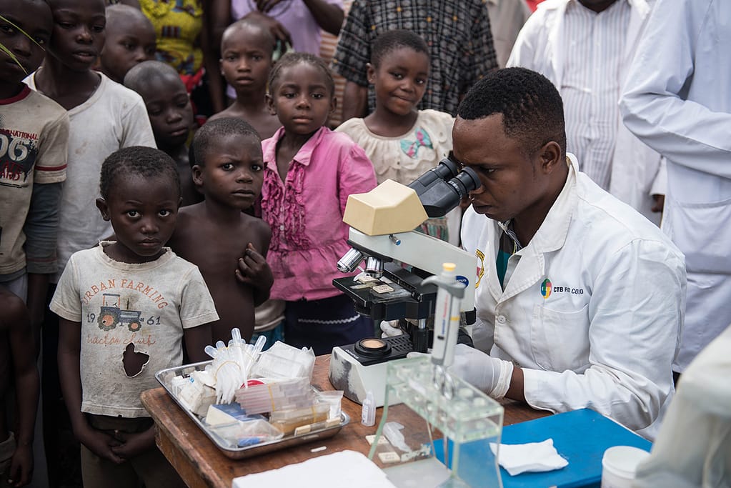 Medical staff looking into a microscope while screening patients in DRC