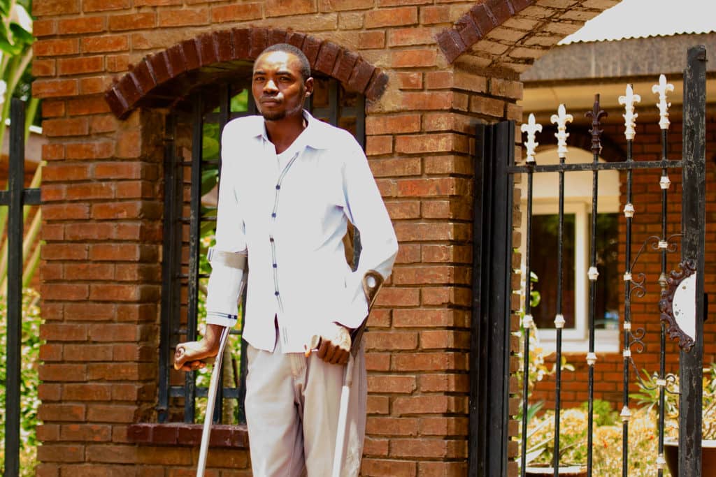 Man standing with crutches in front of the Mycetoma Research Centre