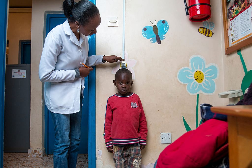 Little boy with paediatric HIV being measured by a nurse in a hospital