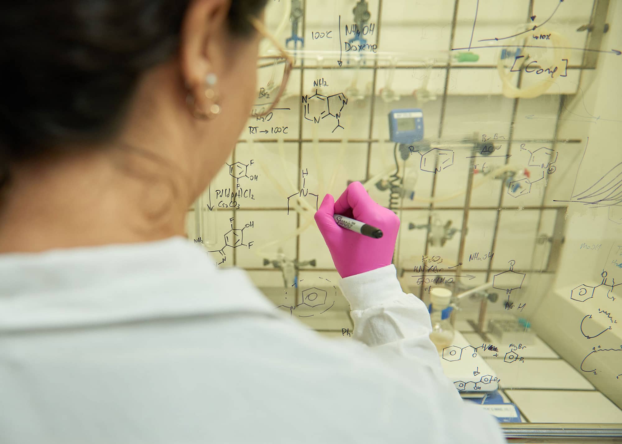 Woman writing chemical formulas on a board